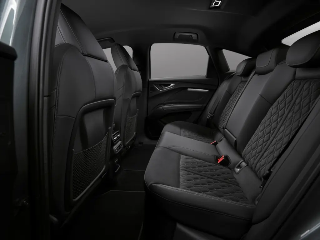 Widok na przestronną tylną kanapę Audi Q4 e-tron z pikowaną tapicerką i dużą ilością miejsca na nogi.
