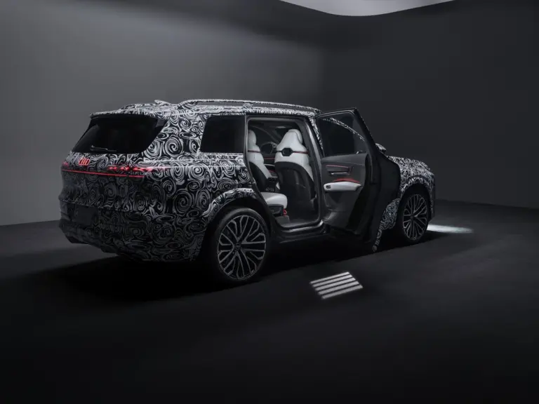 Zamaskowany prototyp Audi Q9 2026 widok od tyłu z otwartymi drzwiami pasażera zdradzającymi białe wnętrze.