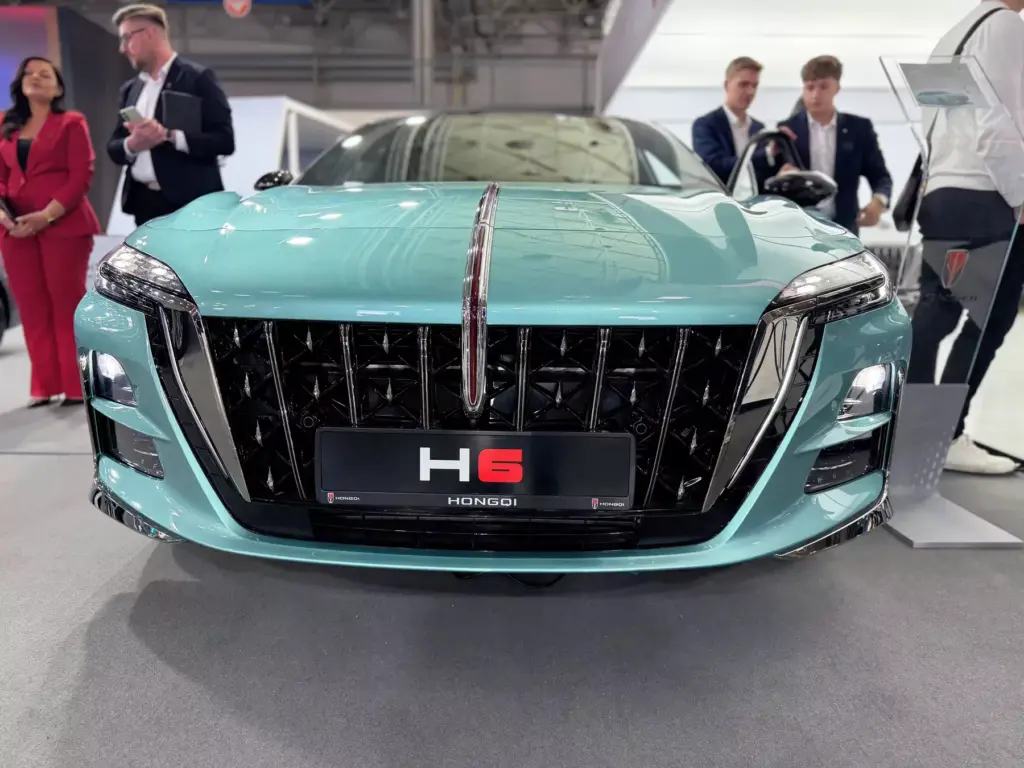 Front modelu Hongqi H6 w kolorze turkusowym z agresywnym wlotem powietrza i logo marki na masce.