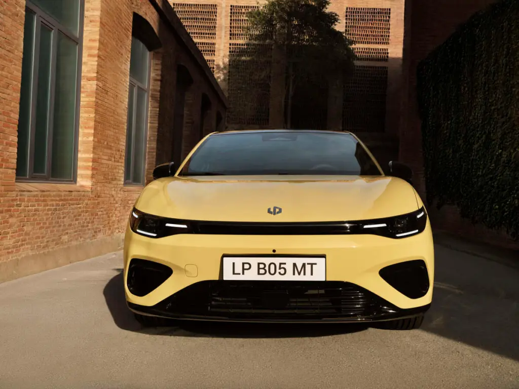 Przód żółtego SUV-a Leapmotor B05 na tle ceglanej architektury, charakterystyczne reflektory LED.