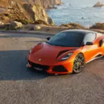 Lotus Emira 420 Sport z przodu na drodze przy wybrzeżu