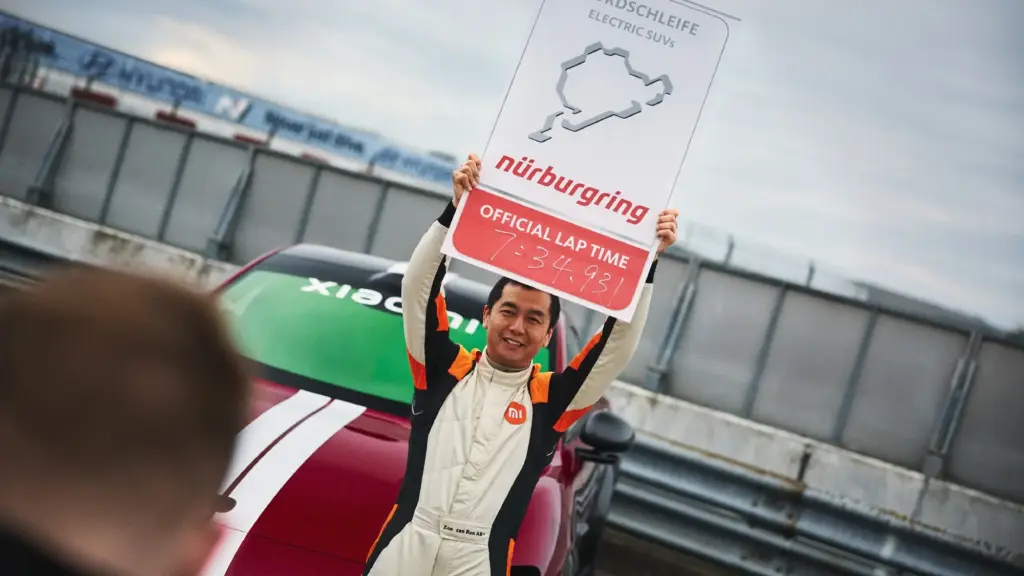 Ren Zhoucan z tablicą Nürburgringu i czasem 7:34,931 obok Xiaomi YU7 GT