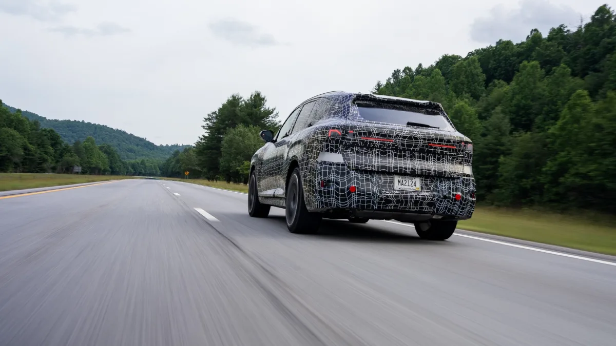 Nowe BMW X5 w kamuflażu od tyłu podczas szybkiej jazdy testowej