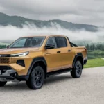 Nowa Toyota Hilux Hybrid 48V w kolorze żółtym na tle górskiego krajobrazu