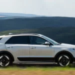 Biała Kia Niro 2027 Hybrid pokazana z boku podczas jazdy