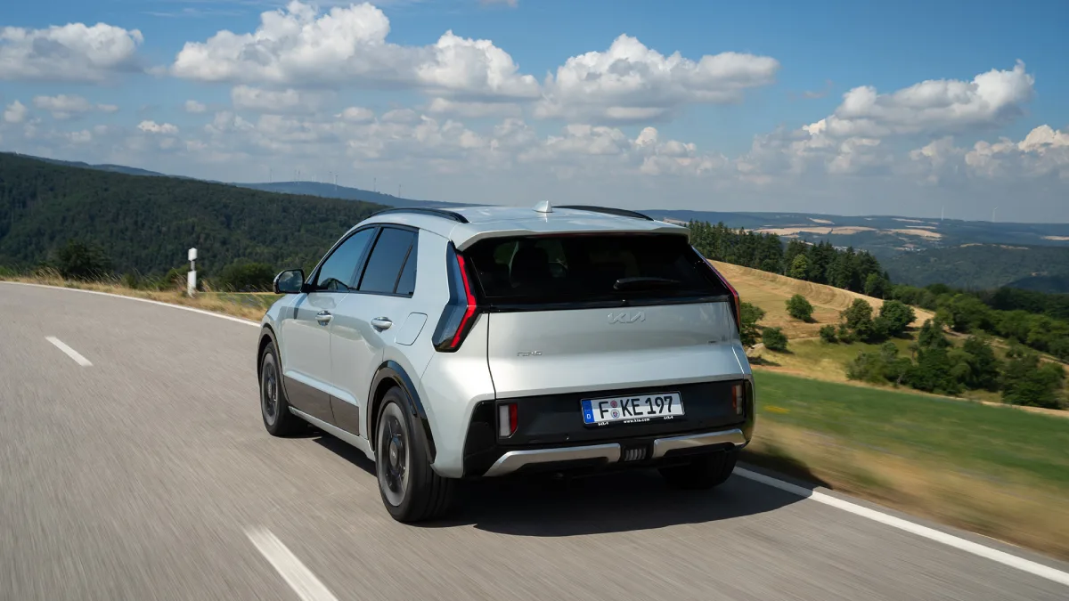 Biała Kia Niro 2027 Hybrid pokazana od tyłu podczas jazdy