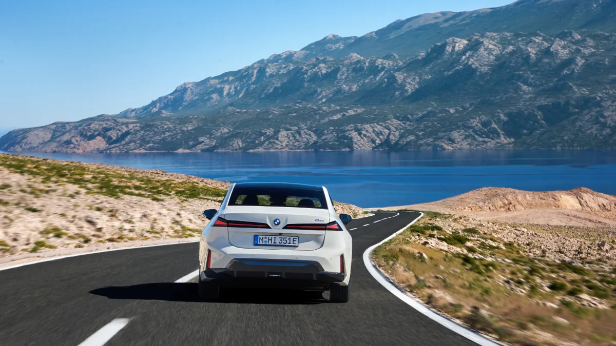 Białe BMW i3 50 xDrive widziane od tyłu podczas jazdy nad wodą