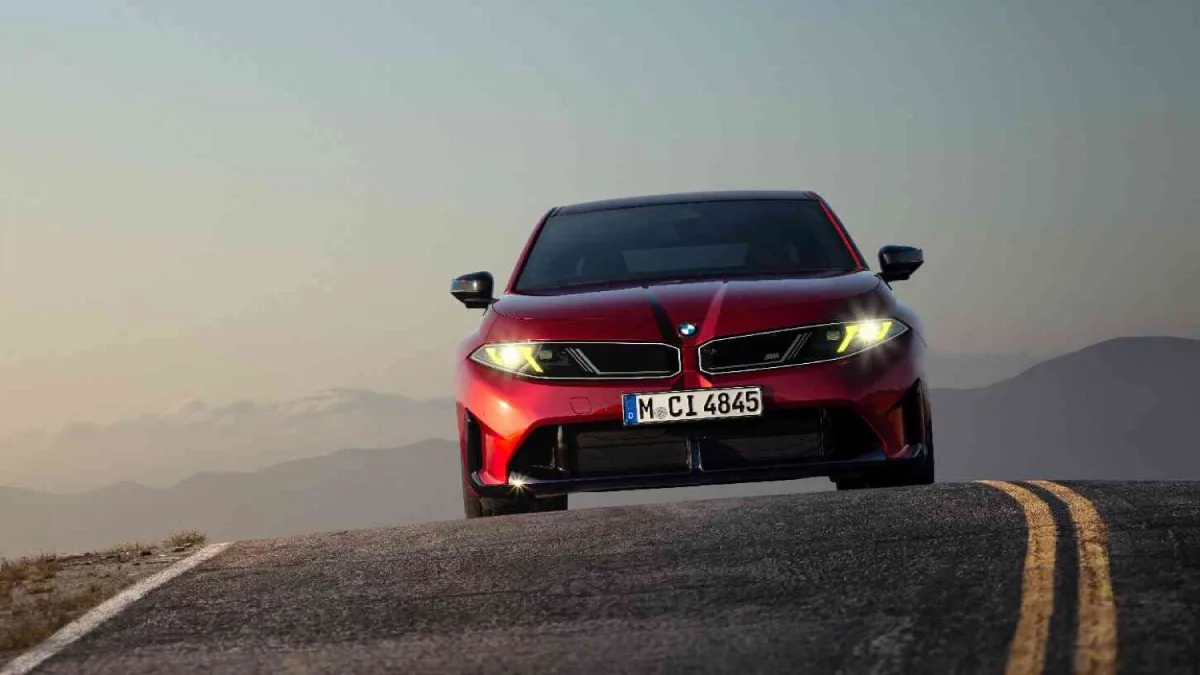 Czerwone BMW serii 3 z żółtymi światłami widziane od przodu na górskiej drodze