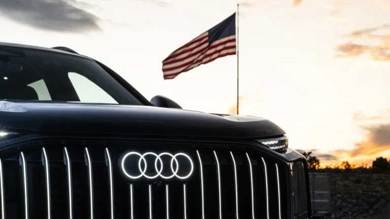 Podświetlone logo Audi na grillu SUV-a i flaga USA w tle, symbolizujące planowaną budowę fabryki Audi w Georgii
