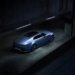 Niebieski Jaguar Type 01 widoczny od tyłu i z boku w betonowym przejeździe