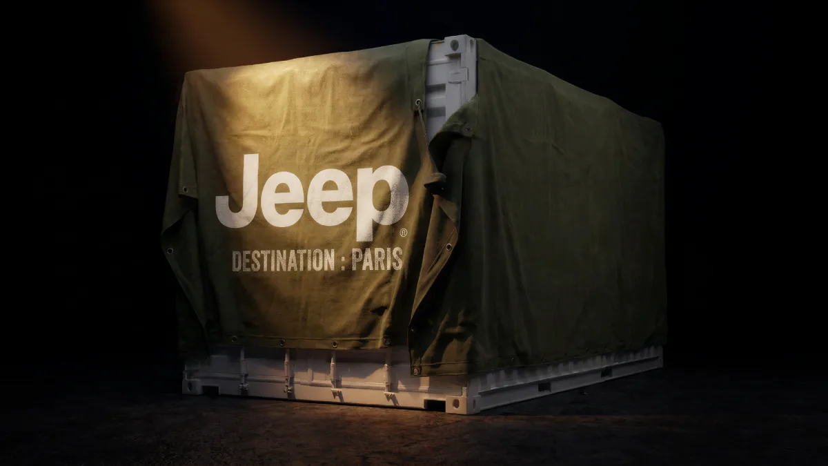 Skrzynia transportowa pod zieloną plandeką z logo Jeep i napisem Destination Paris