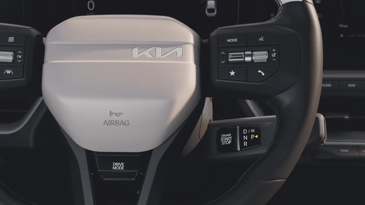Kia K4 Hybrid, zbliżenie wielofunkcyjnej kierownicy z logo Kia, przyciskami sterowania i wybierakiem automatycznej skrzyni biegów