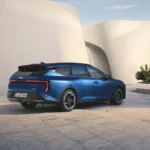 Niebieska Kia K4 Sportswagon Hybrid 2026 widziana z tyłu i boku na tle nowoczesnego budynku
