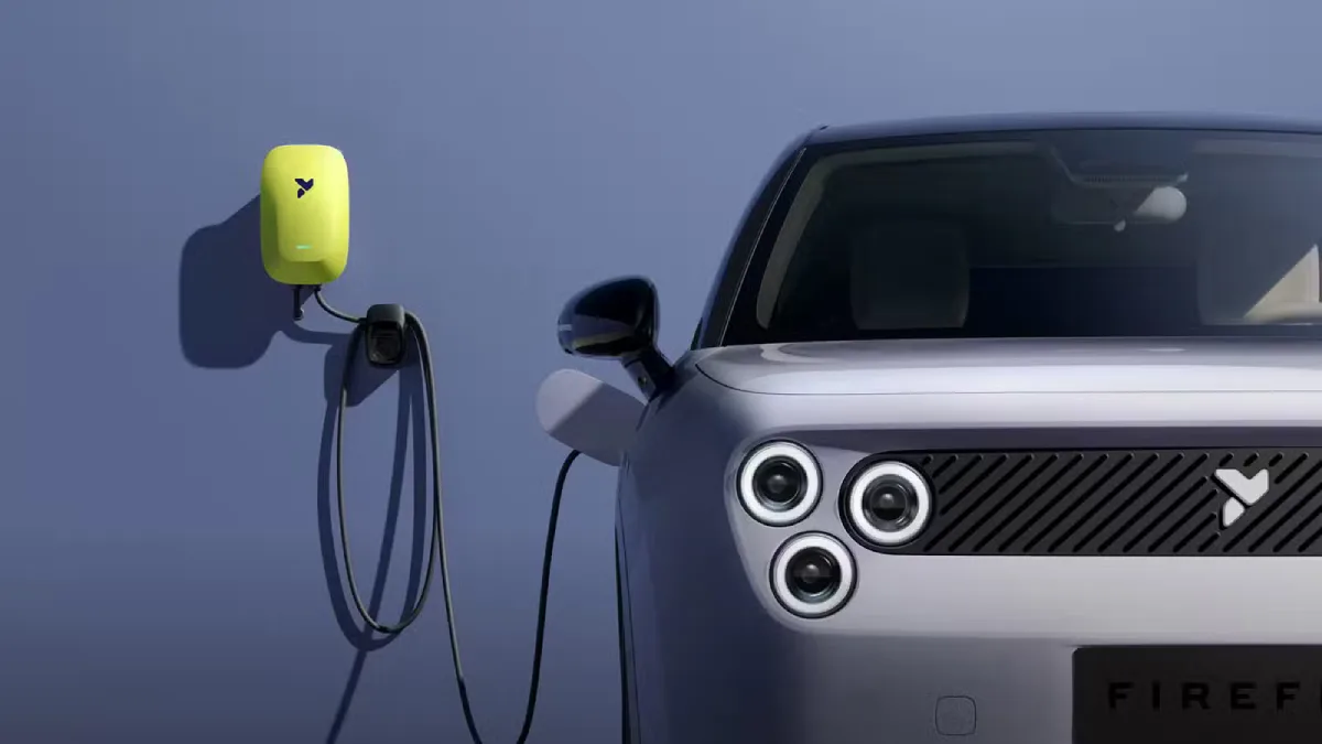 Przednia część elektrycznego Nio Firefly z charakterystycznymi okrągłymi reflektorami obok ściennej ładowarki