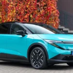 Turkusowy Nissan LEAF 2026 trzeciej generacji widziany z przodu i z boku, z czarnym dachem i polskimi tablicami rejestracyjnymi