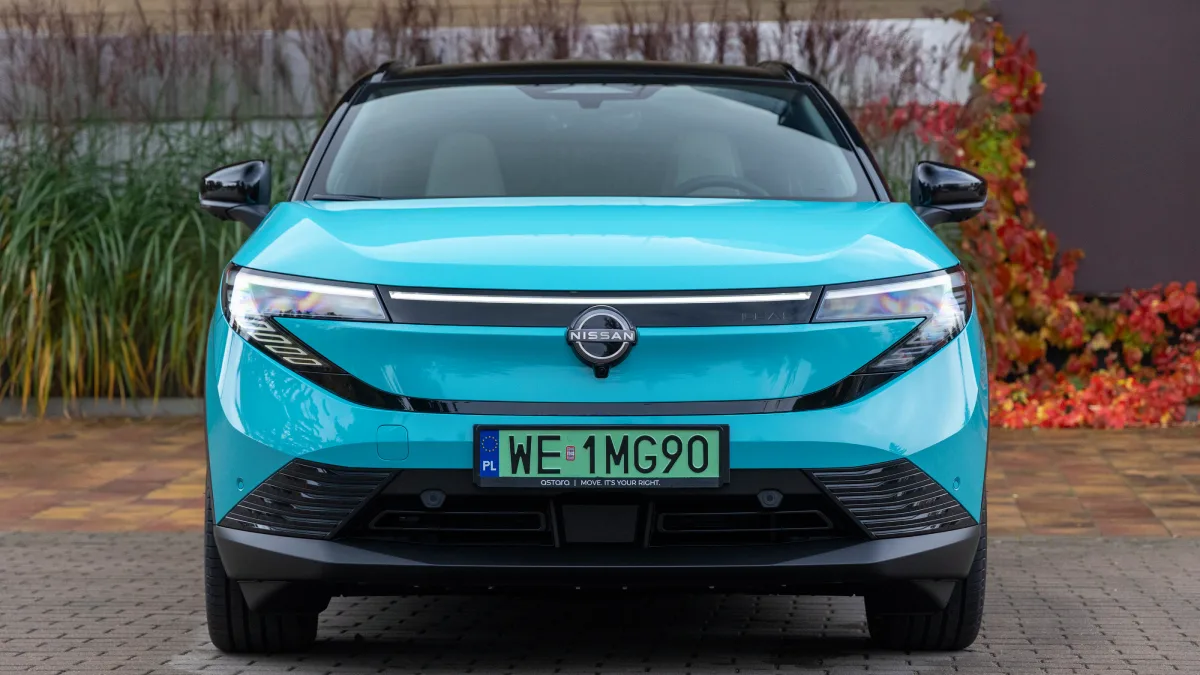 Turkusowy Nissan LEAF 2026 widziany na wprost, z charakterystycznymi reflektorami LED, czarnym dachem i logo Nissan