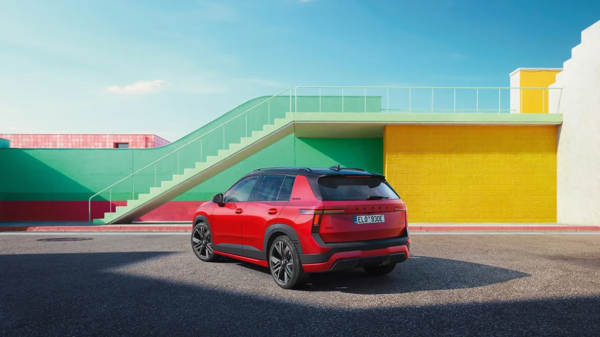 Czerwona Škoda Epiq Sportline widziana z tyłu i boku, z czarnym dachem, tylnymi światłami LED i dużymi obręczami aluminiowymi