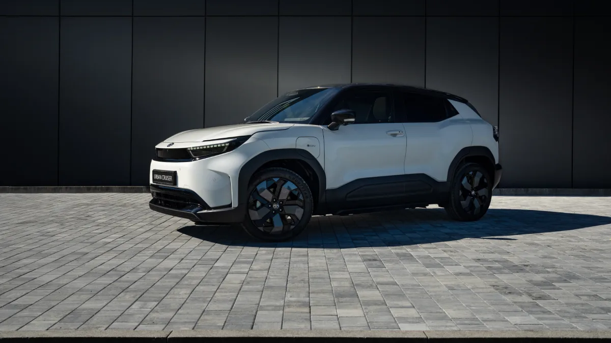 Biała elektryczna Toyota Urban Cruiser z czarnym dachem przed ciemną elewacją budynku